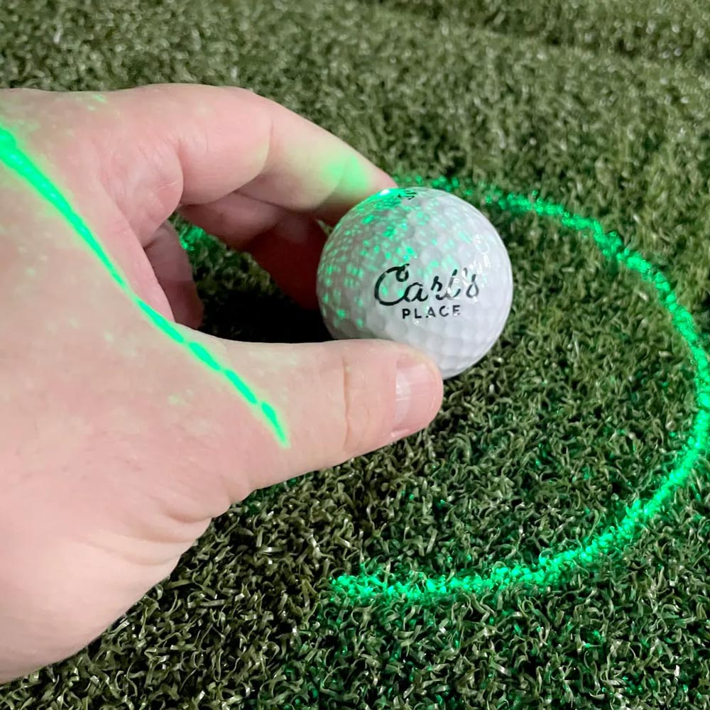 Hand holding golf ball with launch monitor indicators